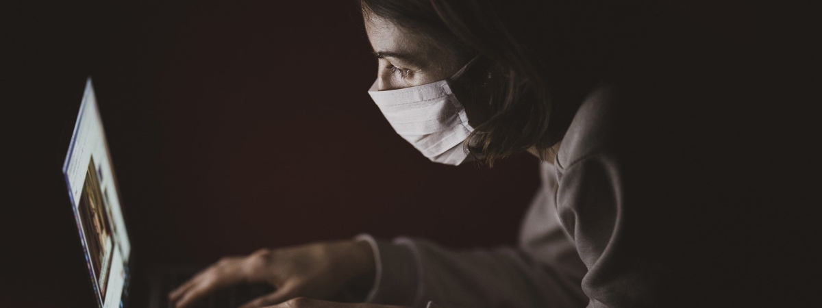 An employee wearing a mask is having an online meeting.